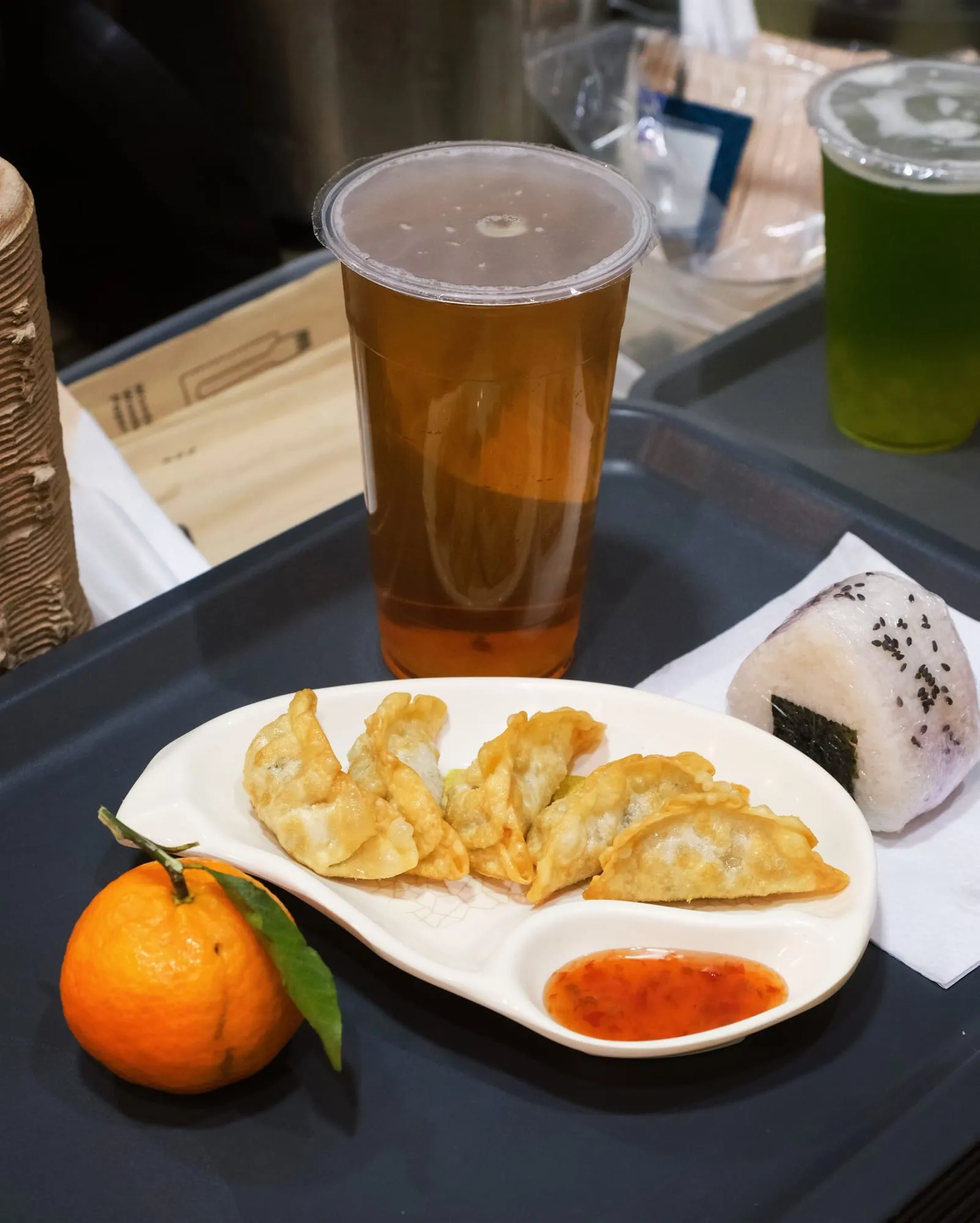 Gyozas grillés, thé glacé et onigiri sur un plateau